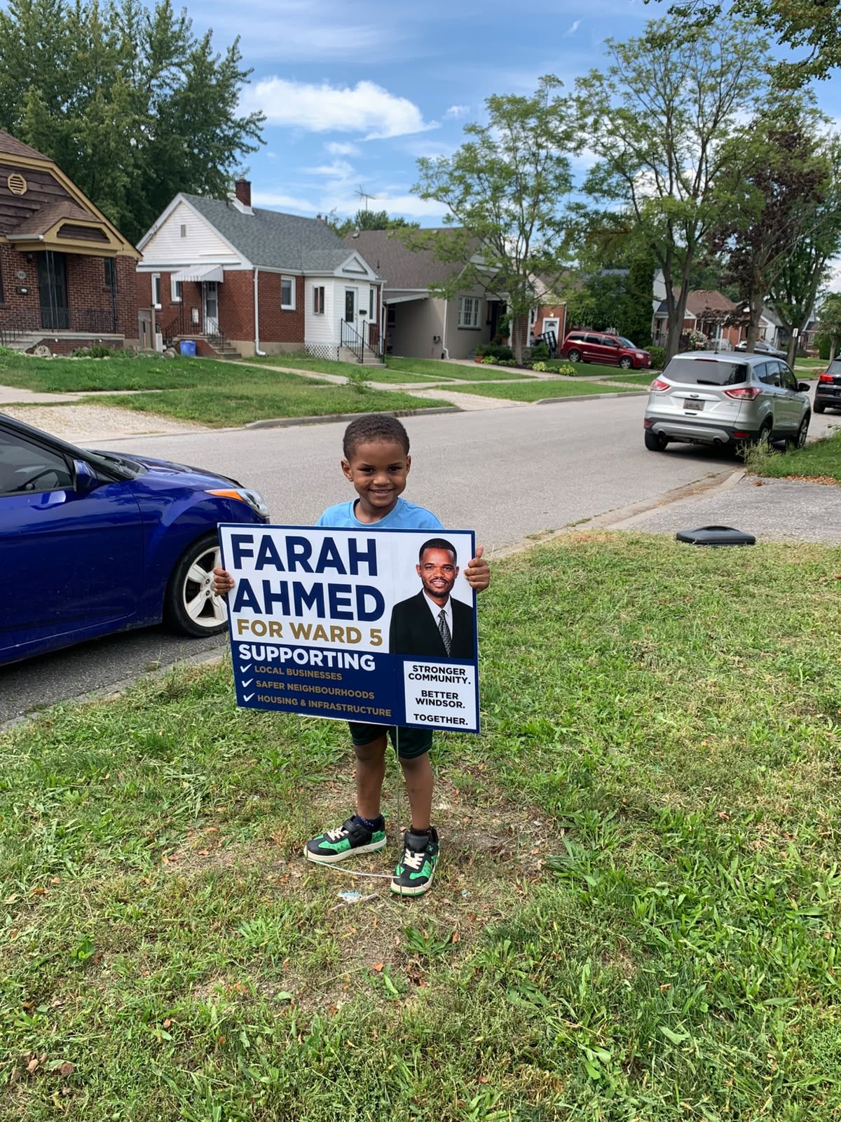 A young Ward 5 supporter holding a Farah Ahmed lawn sign